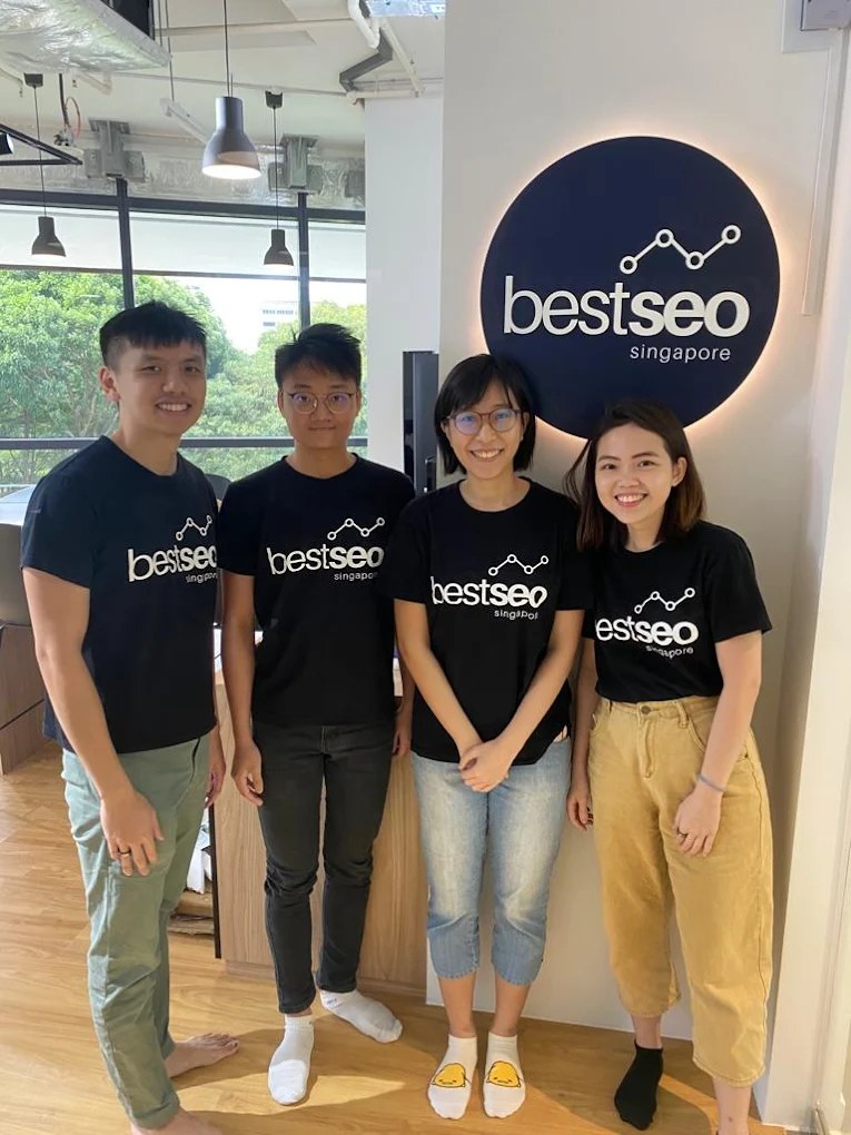 Best SEO Singapore team in branded tees at the BestSEO logo wall